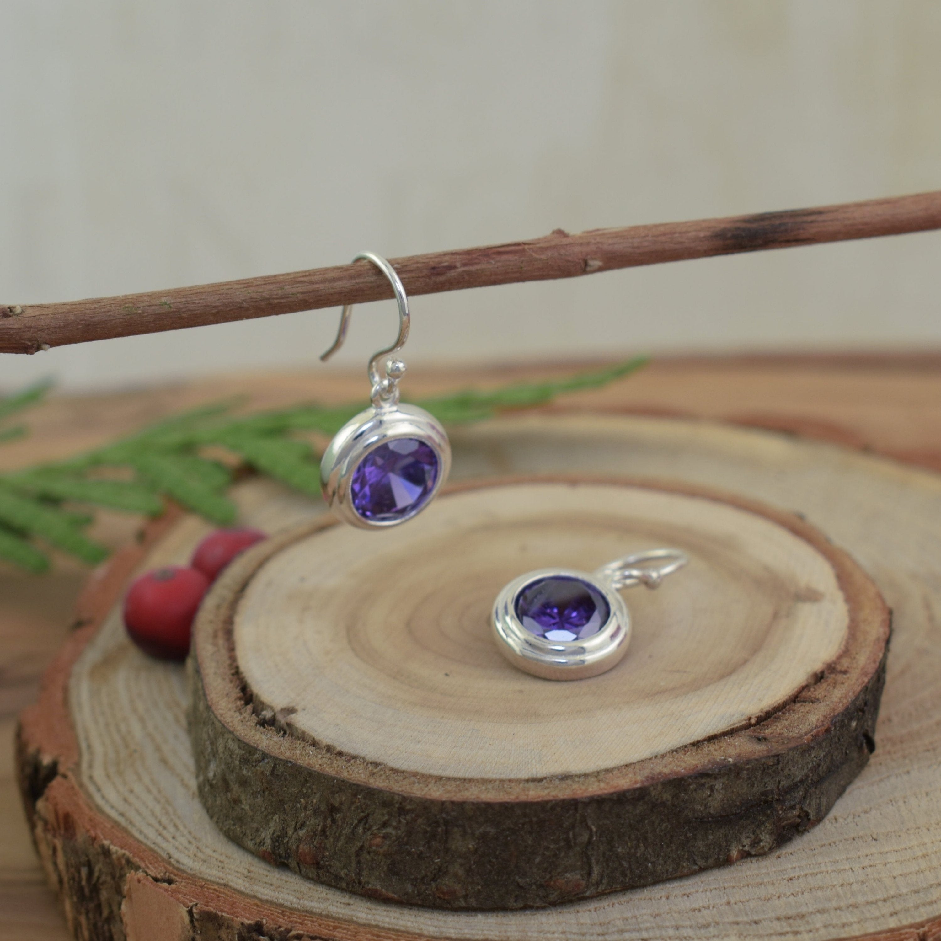 dangling silver earrings featuring round, bezel set purple cz