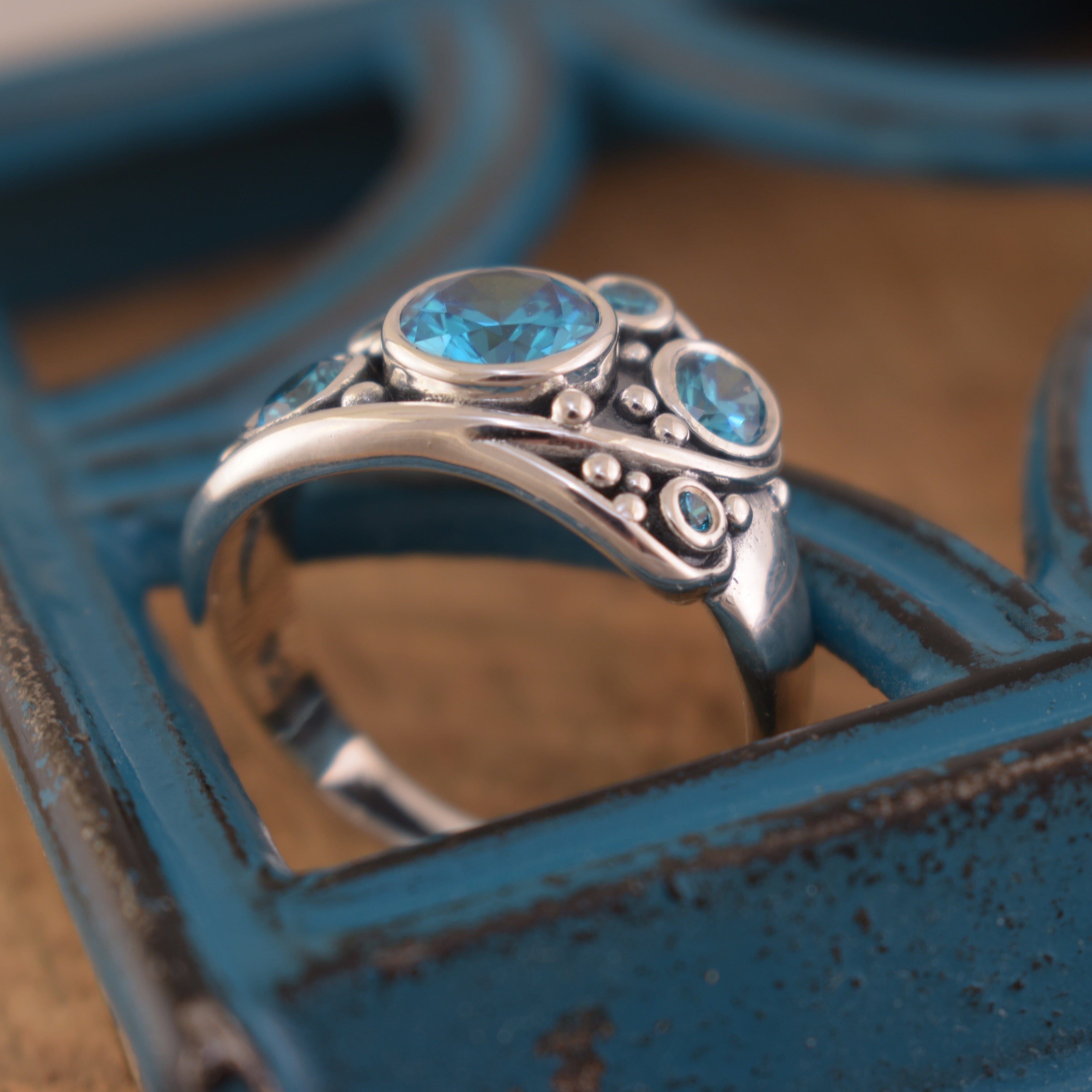 sterling silver ring with blue bezel set cz stones with silver beads around.